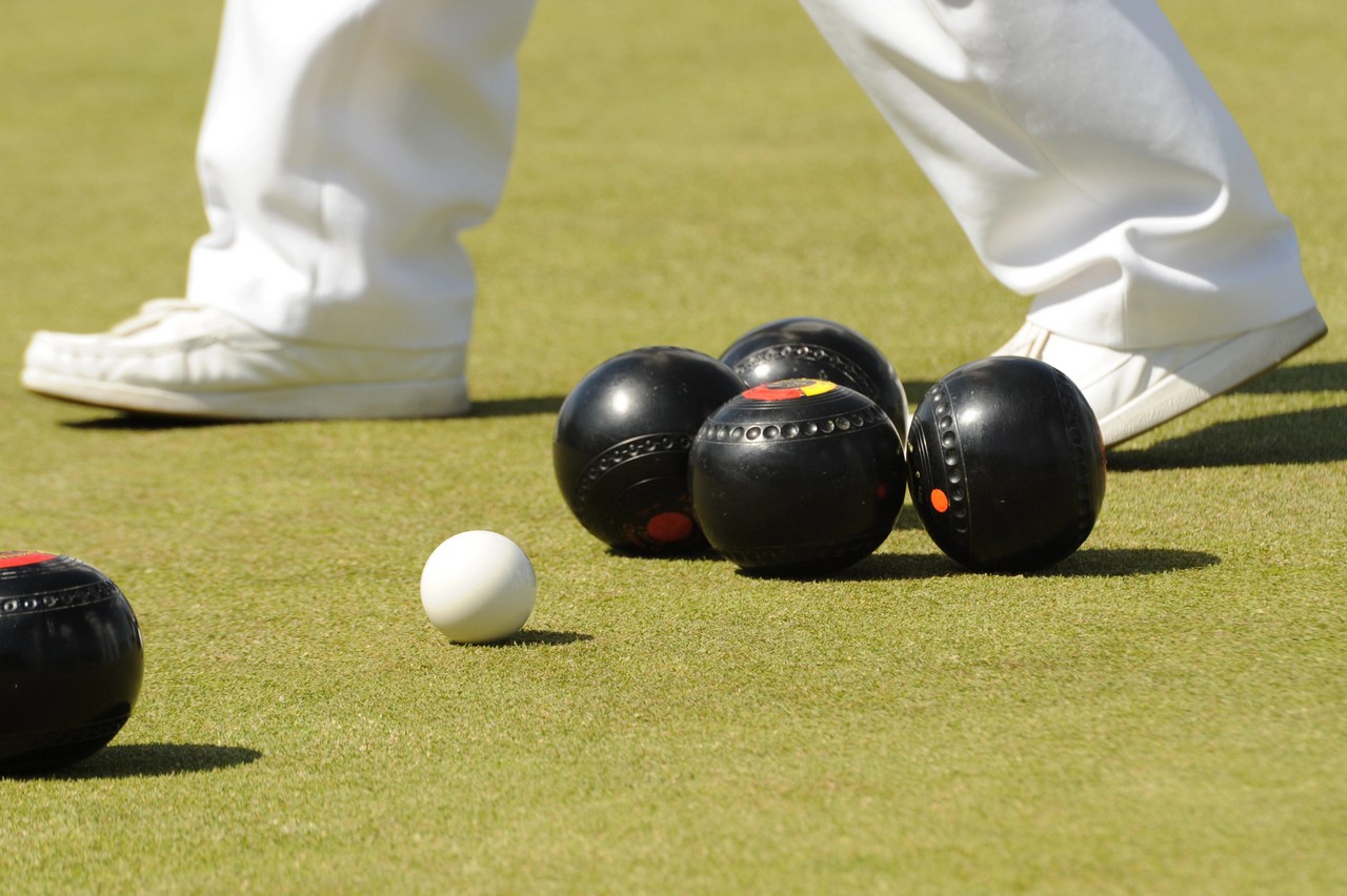 Close-up of lawn bowls gathered around the jack on a manicured green